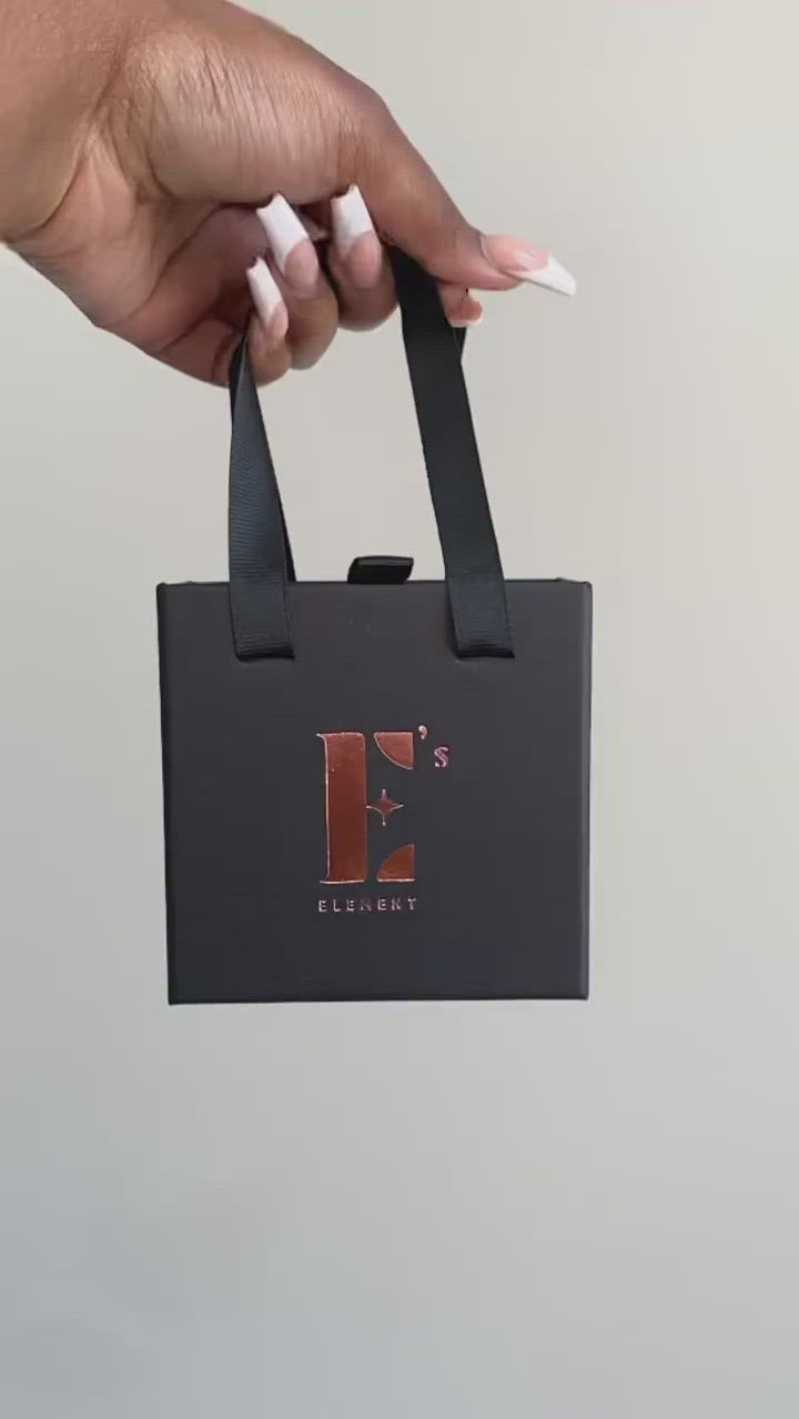 Video of a model holding and spinning a black gift box at the handle. The gift box has the E's Element logo imprinted in gold. 