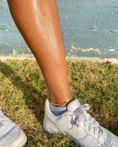 18K gold snake chain anklet worn on the left leg. The subject is wearing "The Steph" Herringbone Anklet by E's Element