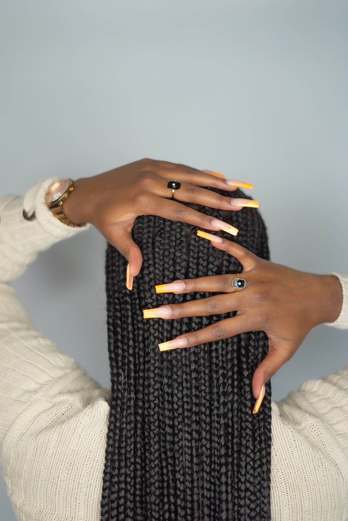 Model in a beige long-sleeve wearing 18k gold ring. Th ring has a zircon stone in the center of a flat rectangular surface in black. Infinity Zircon Ring by E's Element.