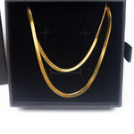 18K gold herringbone chain necklace resting in its container. Named "The Steph" Herringbone Chain Necklace by E's Element.