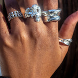 Model wearing 18k silver molten rings on her thumb, index, and middle finger. The model is also wearing two 18k silver chain rings on her ring finger. Ella Lava Ring Trio (Set of 3) by E's Element.