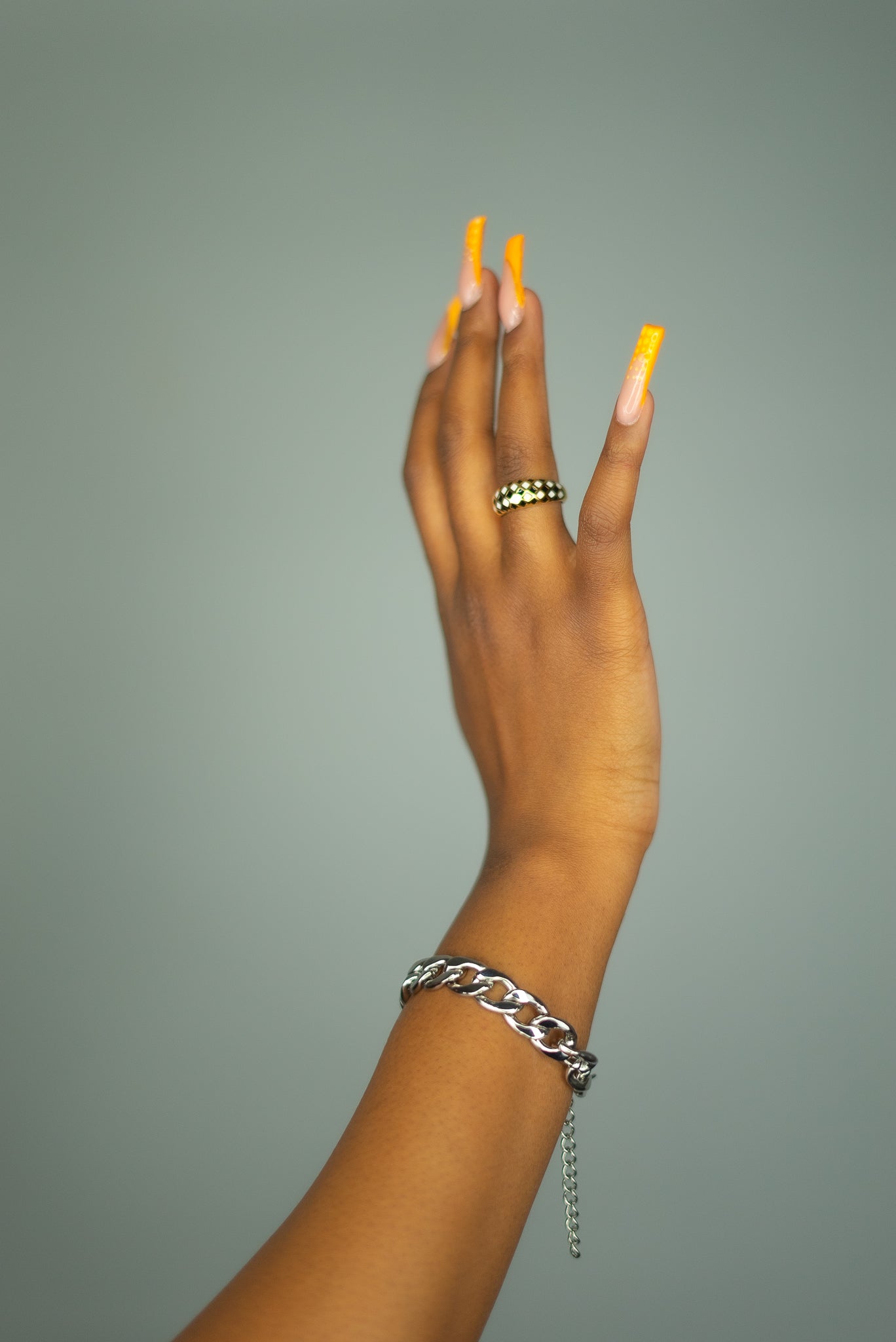 Model wearing an 18k gold ring with black and white diamond dots. The model is also wearing a silver chain bracelet. Minimalist Resin Ring by E's Element.