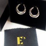 18K silver stainless steel hoop earrings in its container. There is a polishing cloth underneath with E's Element logo printed in yellow. Alyssa Hoops by E's Element.