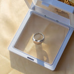 18k silver signet ring resting in a white container on a table with a beige cloth. Ellina Heart Signet Ring by E's Element.