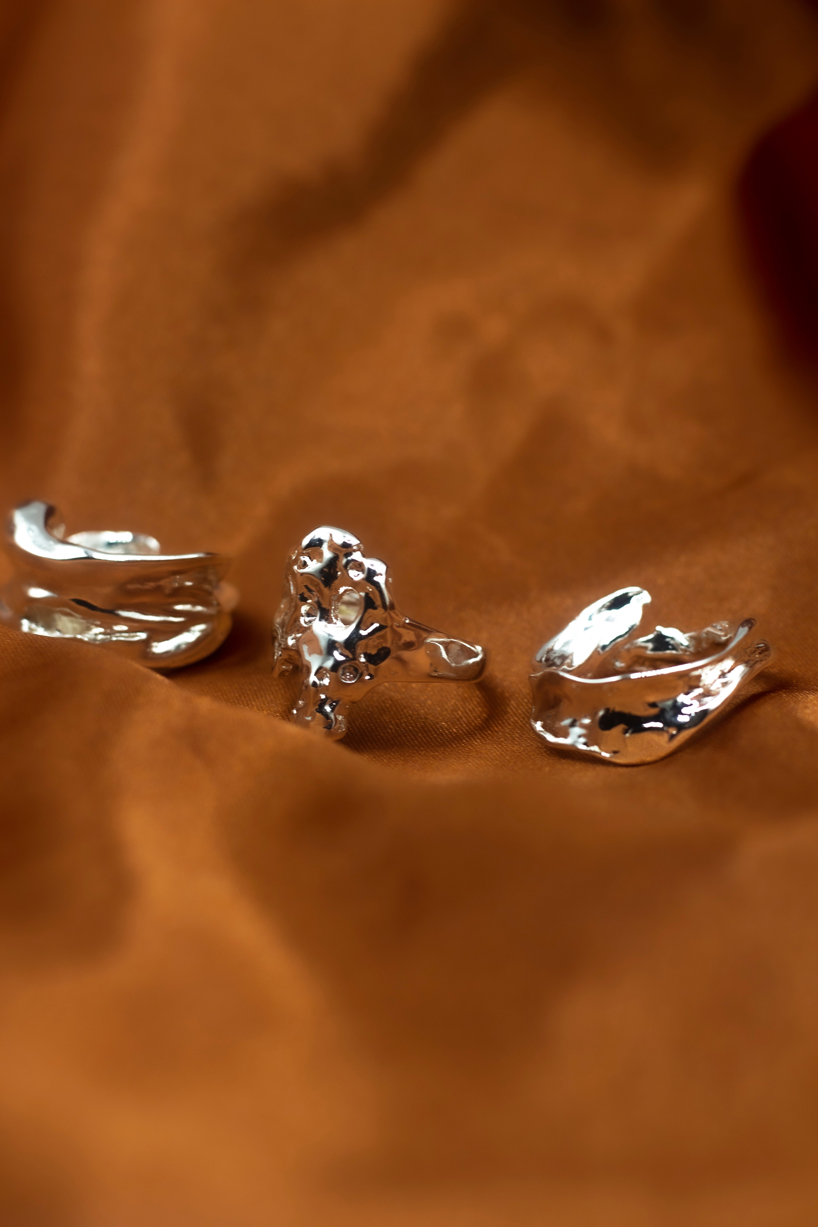 18k silver molten rings place side-by-side on an orange cloth. Ella Lava Ring Trio (Set of 3) by E's Element.