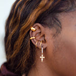 Side profile of model wearing 18k gold spiral ear cuff. She is also wearing a drop earring with a cross charm. Unisex Spiral Ear Cuffs - E's Element.